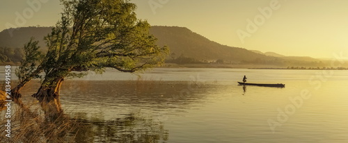 river view morning of alone tree and a fishing boat rowing in Mekong river in Khong Chiam, Ubon Ratchathani, Thailand. photo