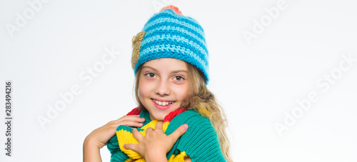 Which fabrics will keep you warmest this winter. Girl long hair happy face white background. Kid wear warm soft knitted blue hat and long scarf. Warm woolen accessories. Hat and scarf keep warm