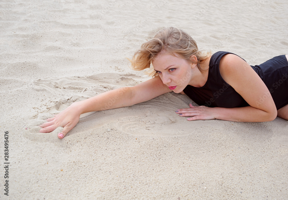 Passionate young woman in a black swimsuit lying on the sand. Summer holiday. Passionate young woman in a black swimsuit lying on the sand. Summer holiday.