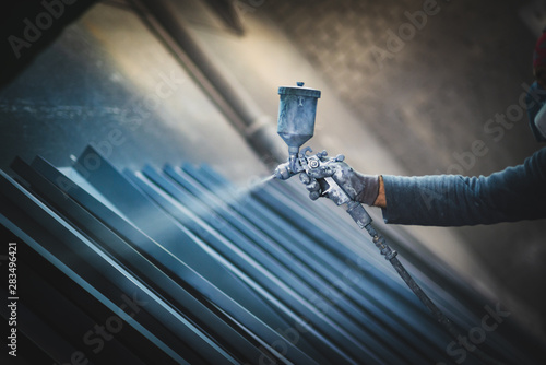 Man painting metal products with a spray gun photo