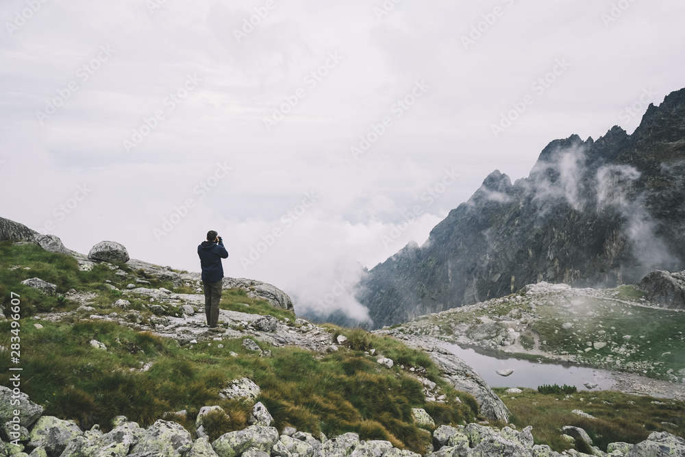 Man Filming The Clouds In Mountains