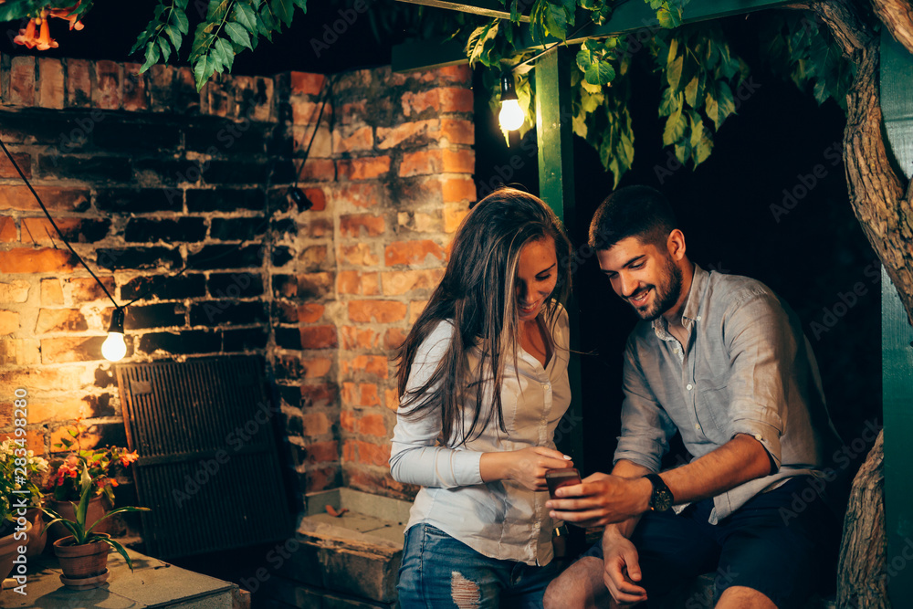 young couple using smartphone outdoor in backyard young couple using smartphone outdoor in backyard