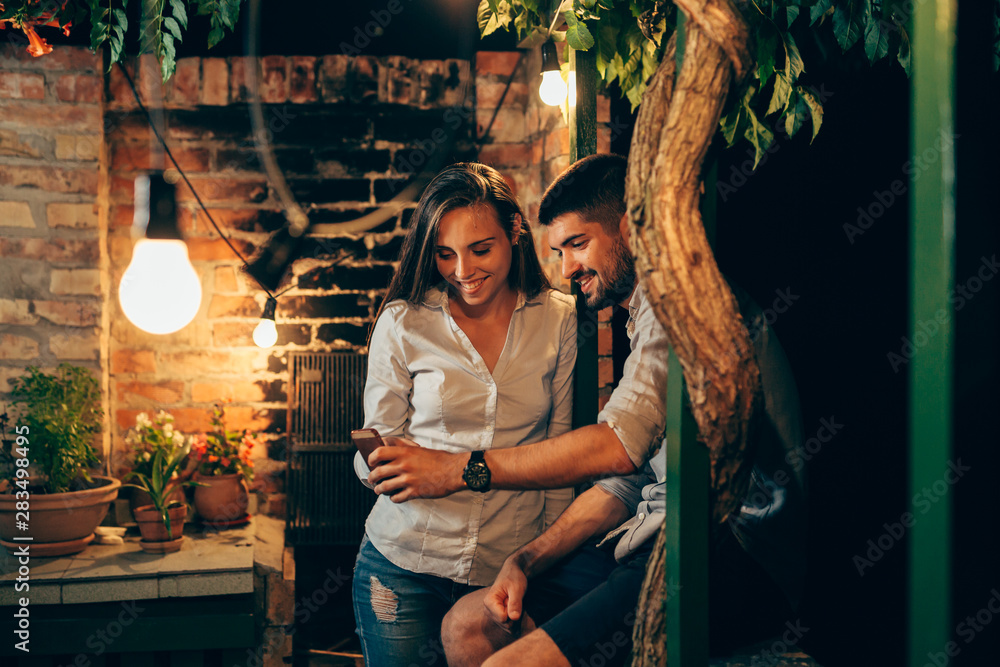 young couple using smartphone outdoor in backyard