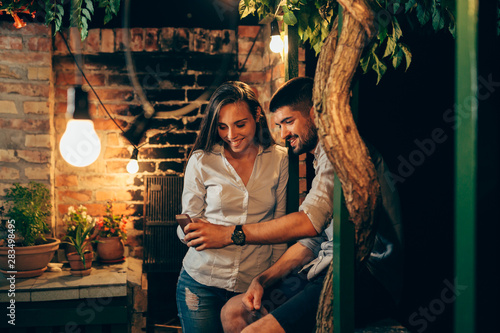 young couple using smartphone outdoor in backyard