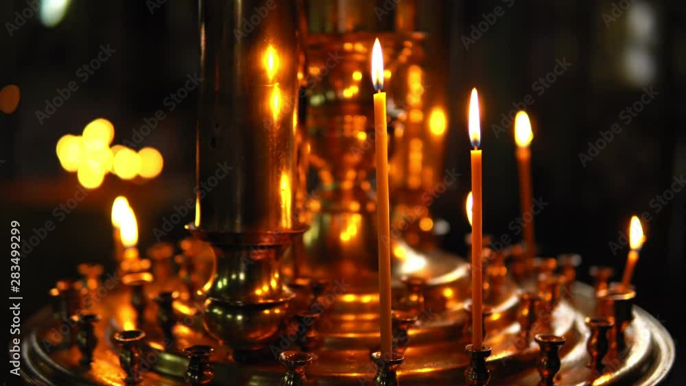 Burning candles in a gold candlestick in a dark room of the Orthodox Church, close-up Burning candles in a gold candlestick in a dark room of the Orthodox Church, close-up
