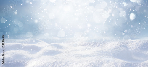 Winter snow background with snowdrifts, with beautiful light and snow flakes on the blue sky, beautiful bokeh circles, banner format, copy space. © Laura Pashkevich
