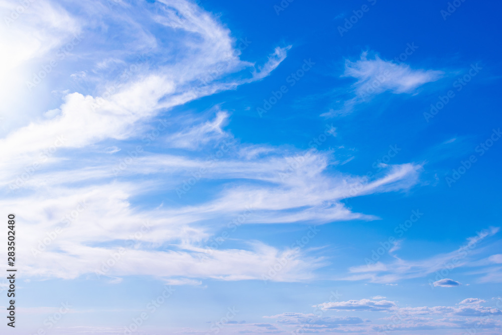 Blue background of the sky and feathery clouds. Light fibrous, airy formations, fibers randomly scattered across the sky