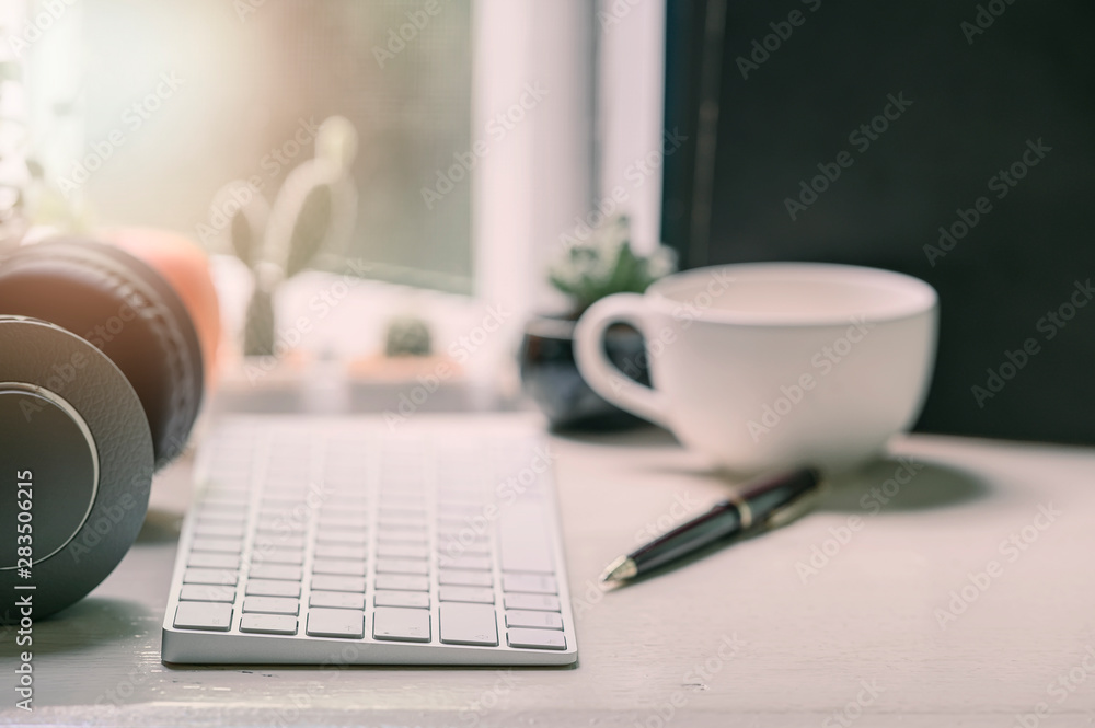 white keyboard computer, books and supplies on wooden table with sunlight over window, workspace concept. white keyboard computer, books and supplies on wooden table with sunlight over window, workspace concept.
