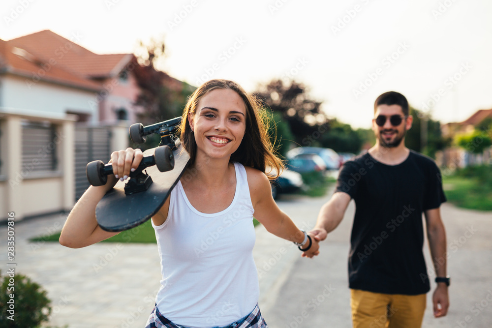beautiful happy young couple driving skateboard outdoor