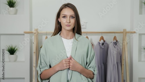 beautiful lady with loose hair and nice smile in fair green pantsuit standing against white wall close view photo