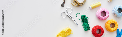panoramic shot of zipper, scissors, threads, knitting yarn balls, tracing wheel, measuring tape on white background