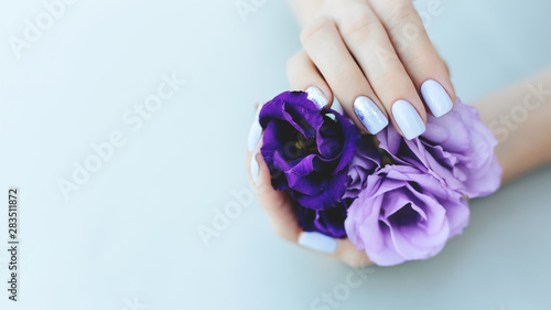 Purple manicure on a light purple background with a flower.
