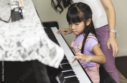 Asian family Mother and daughter playing piano, music concept.