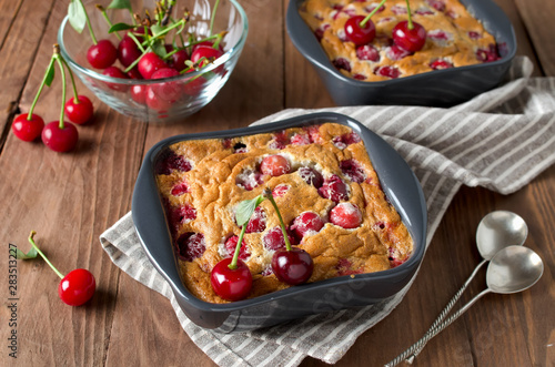Cherry clafouti in portional ceramic forms on rustic wooden background.