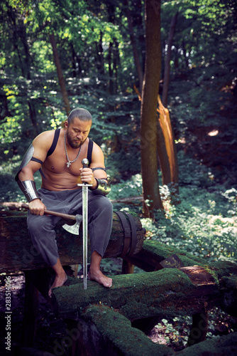 Muscular and strong man with ax and sword