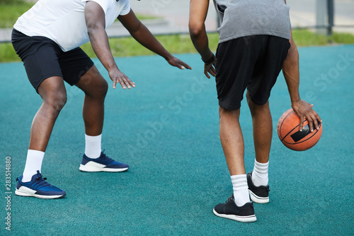 Back view low angle of two African-American guys playing basketball outdoors, copy space