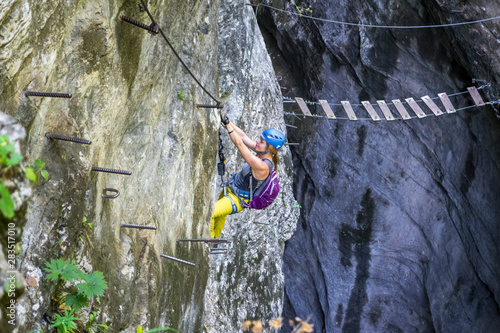 Relaxed girl down-climbing a via ferrata section on a route called 
