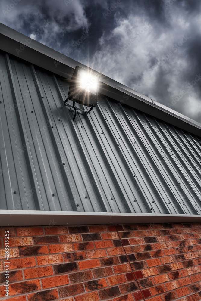 Security Light Mounted On A Factory Wall - obrazy, fototapety, plakaty 