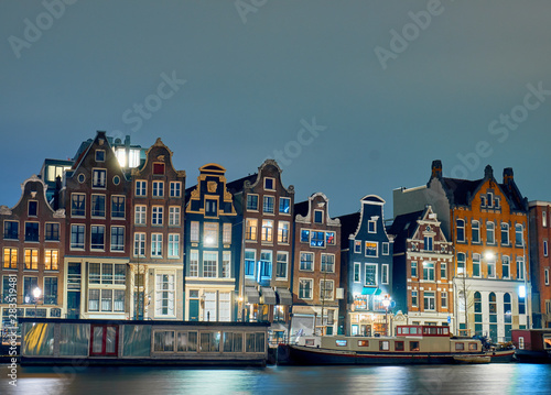 Housebots and old buildings by the canal at night in Amsterdam.