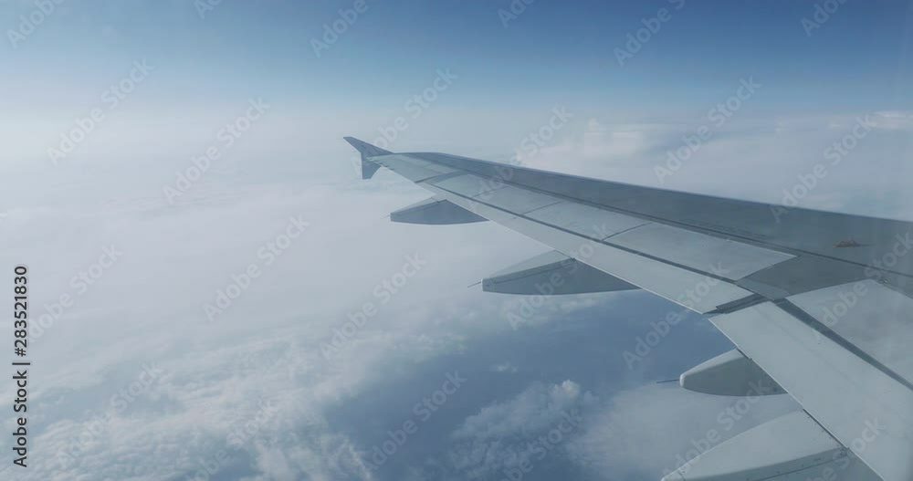 View on blue sky and fluffy white clouds through the window of the aircraft. Scenic view from flying airplane. View on blue sky and fluffy white clouds through the window of the aircraft. Scenic view from flying airplane.