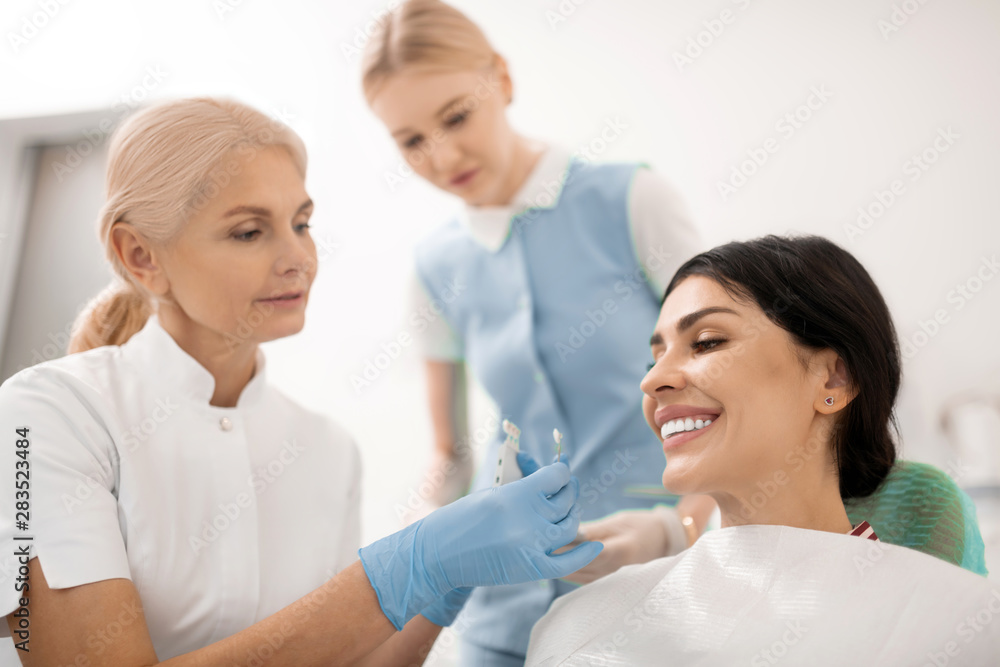 Dentist trying teeth whitening samples for her patient. Dentist trying teeth whitening samples for her patient.