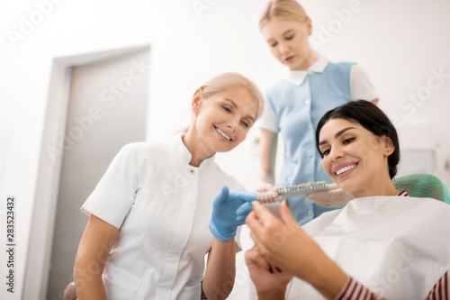 Dentist helping her patient choosing teeth whitening samples.