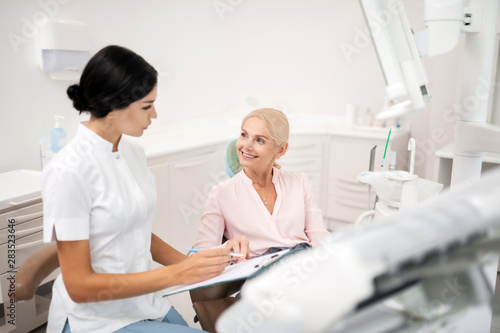 Cheerful patient asking her dentist about procedures.