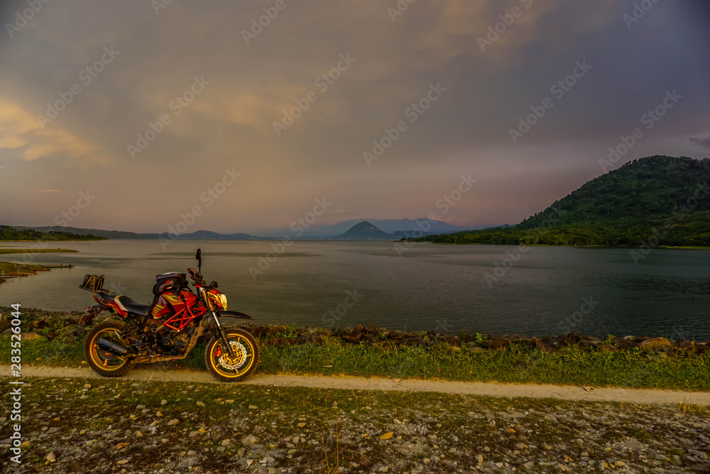 Fototapeta premium Purwakarta, West Java, Indonesia (03/30/2018) : The rider is touring with his motorcycle through the Jatiluhur Dam side which is commonly called Parang Gombong