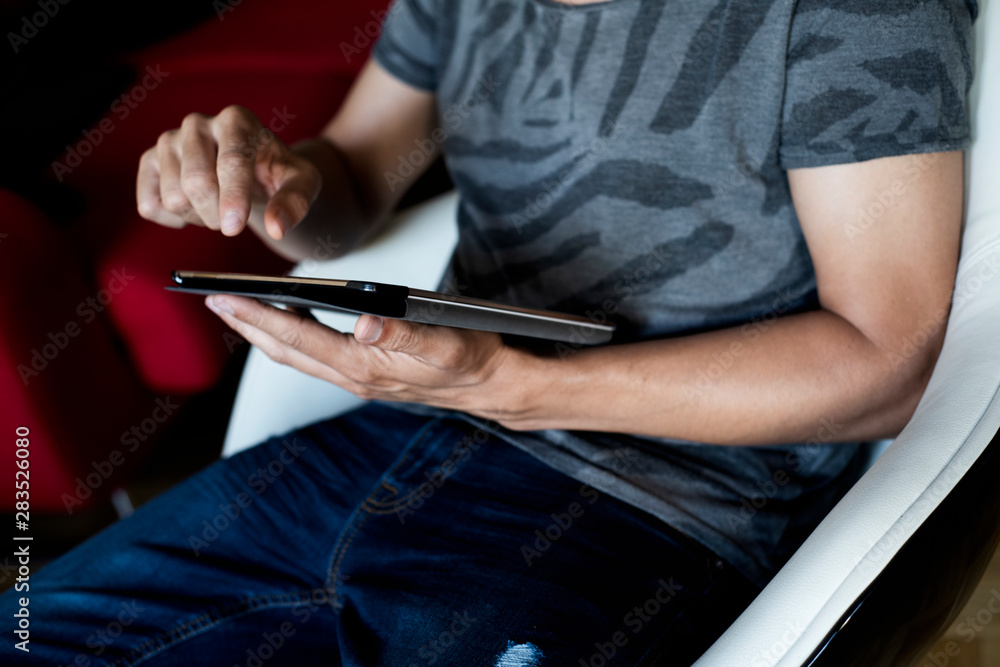young man using a tablet sitting in an armchair.