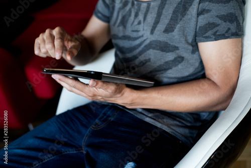 young man using a tablet sitting in an armchair.