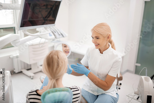 Dentist showing the patient her teeth in the mirror.