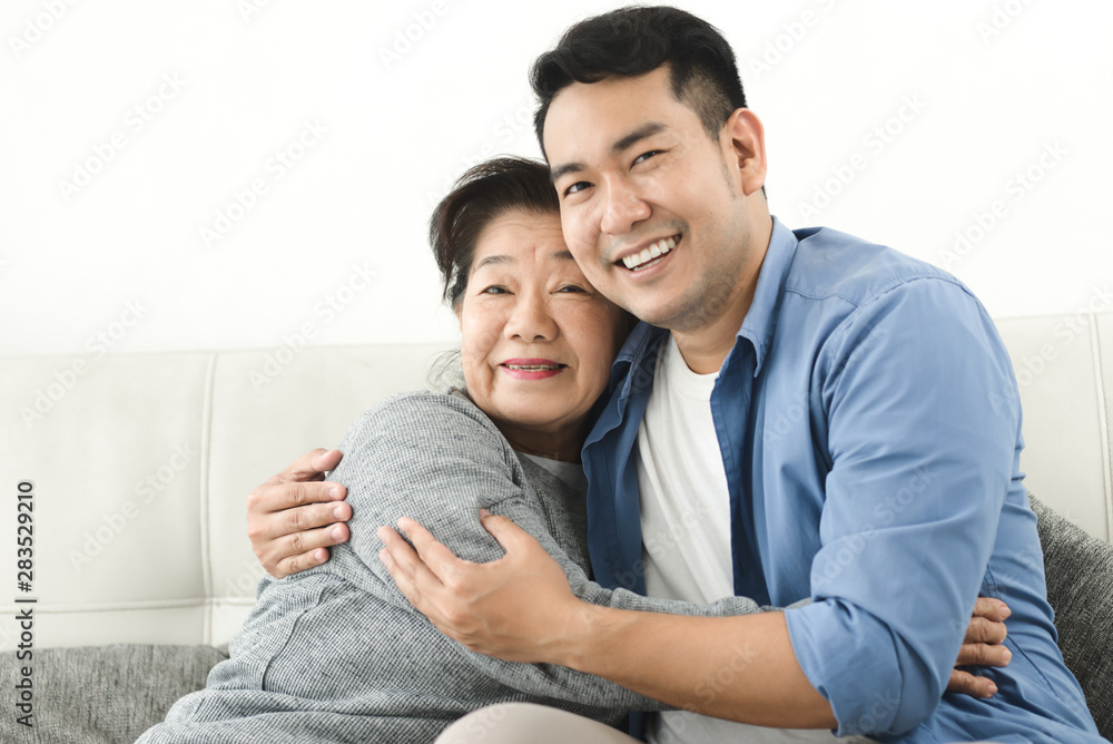 Asian mother hugging her son and sitting on sofa at home, lifestyle concept. Asian mother hugging her son and sitting on sofa at home, lifestyle concept.