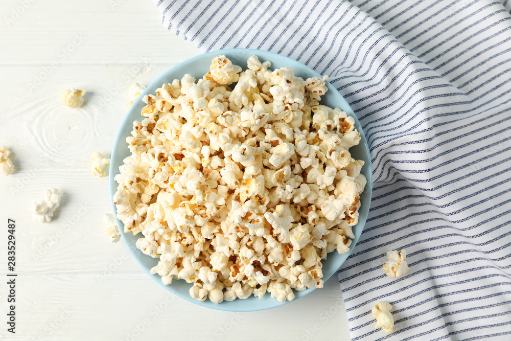 Flat lay composition. Towel and plate with popcorn on white wood background Flat lay composition. Towel and plate with popcorn on white wood background