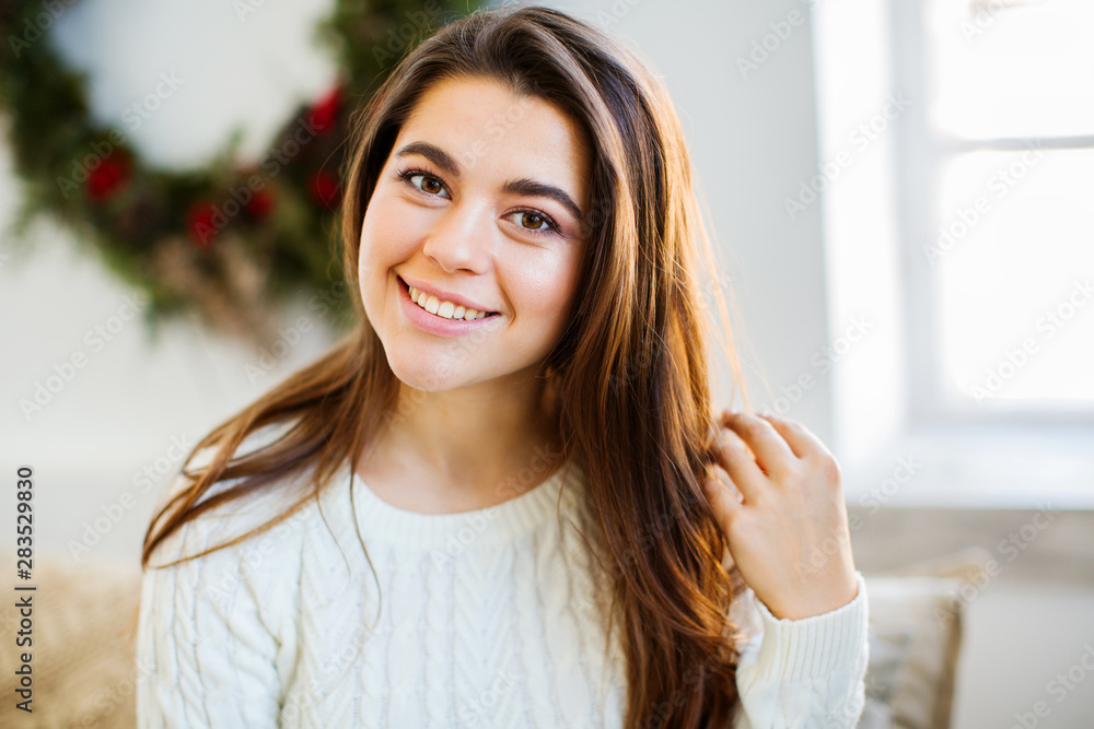 Young attractive woman in white cozy sweater near the New Year tree. Young attractive woman in white cozy sweater near the New Year tree.