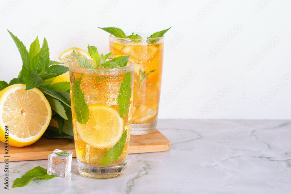 Glass of iced tea with mint and lemon on marble table. Cold drink. Glass of iced tea with mint and lemon on marble table. Cold drink.
