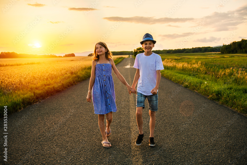 Two Children brother and sister on a hay field at the sunset Two Children brother and sister on a hay field at the sunset