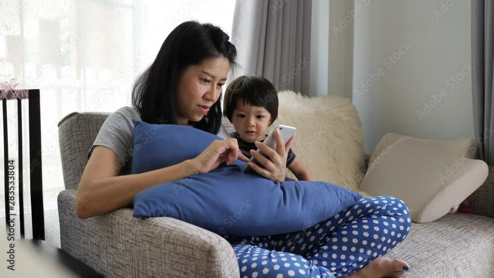 mother and son playing mobile phone in living room mother and son playing mobile phone in living room