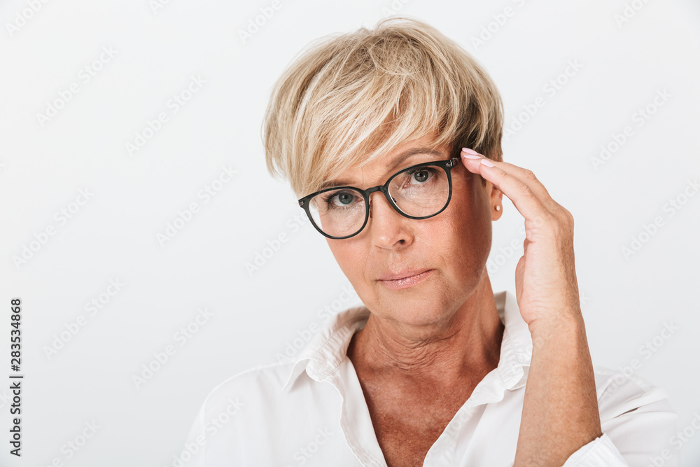Portrait of smart adult woman looking at camera and touching her eyeglasses