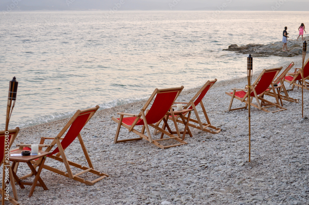 Beach chairs with flambeau at sunset background on Adriatic sea in Brela, Croatia