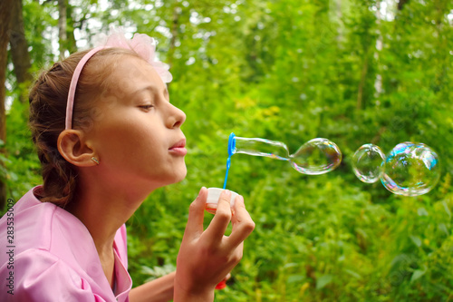 Beautiful girl inflates soap bubbles. Cheerful happy action at the child.