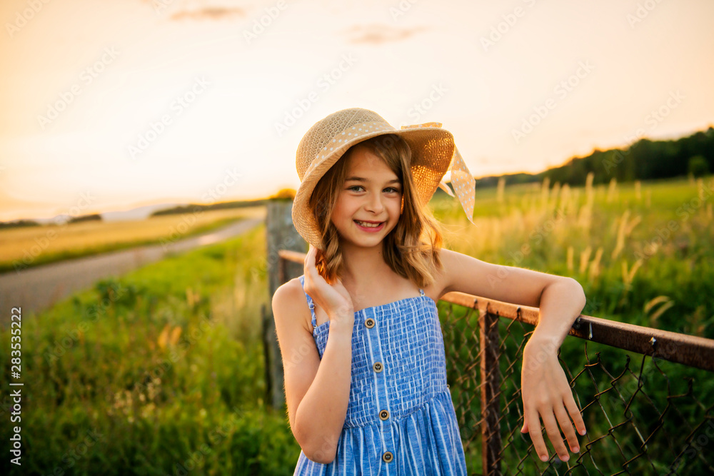Child girl on a hay field at the sunset
