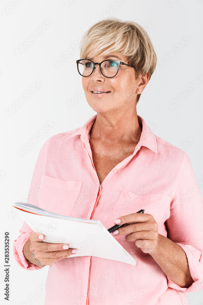 Portrait of mature adult woman wearing eyeglasses writing notes in exercise book Portrait of mature adult woman wearing eyeglasses writing notes in exercise book