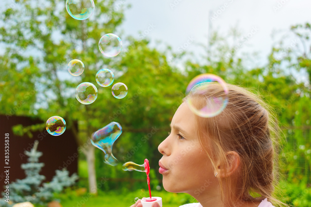 Beautiful girl inflates soap bubbles. Cheerful happy action at the child.