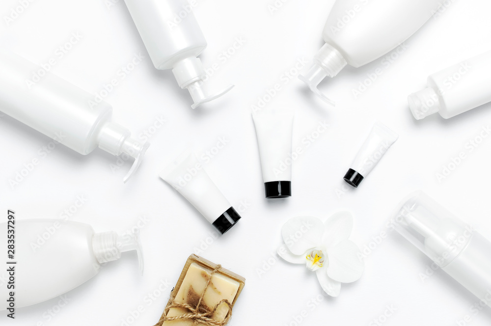 White cosmetic bottle containers, natural soap, orchid flower on white background top view flat lay. Cosmetics SPA branding mock-up. Natural organic beauty product concept. Minimalism cosmetics style White cosmetic bottle containers, natural soap, orchid flower on white background top view flat lay. Cosmetics SPA branding mock-up. Natural organic beauty product concept. Minimalism cosmetics style