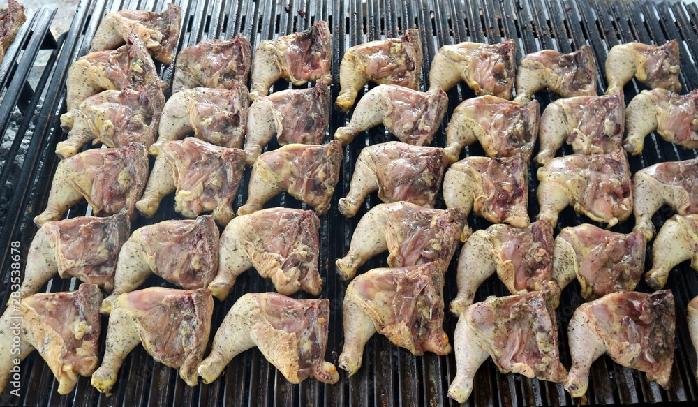 Lots of chicken leg quarters on a large grill for a summer barbecue. They have just been put.