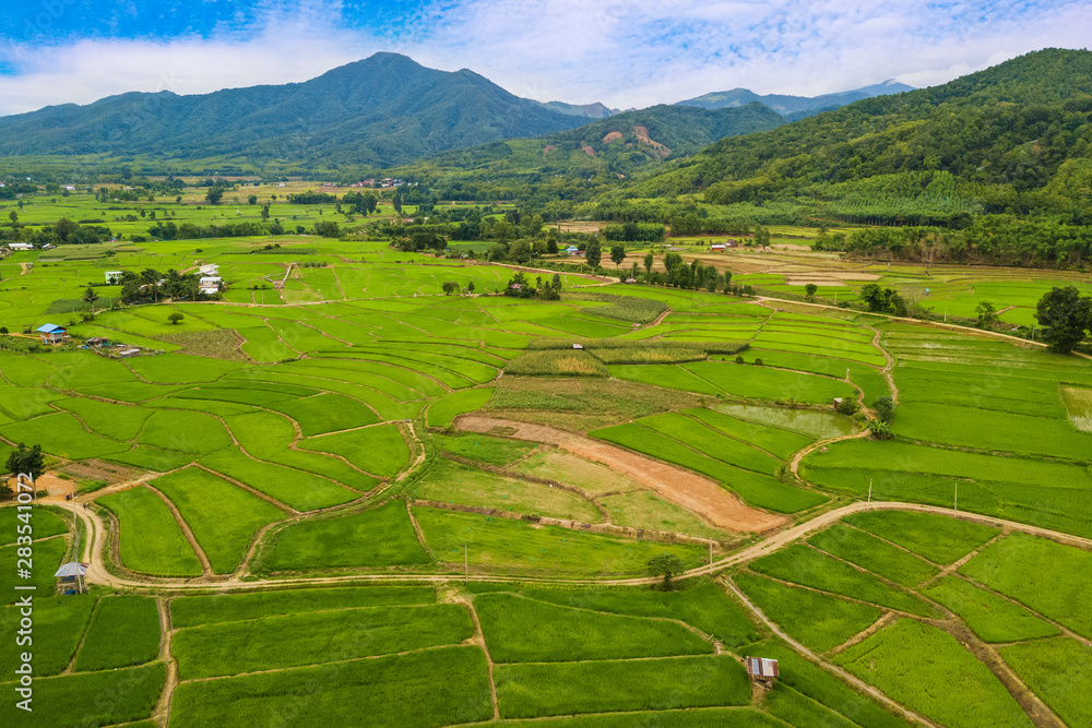 Aerial view over rice terraces field and village with mountain background,Nan,Northern of Thailand