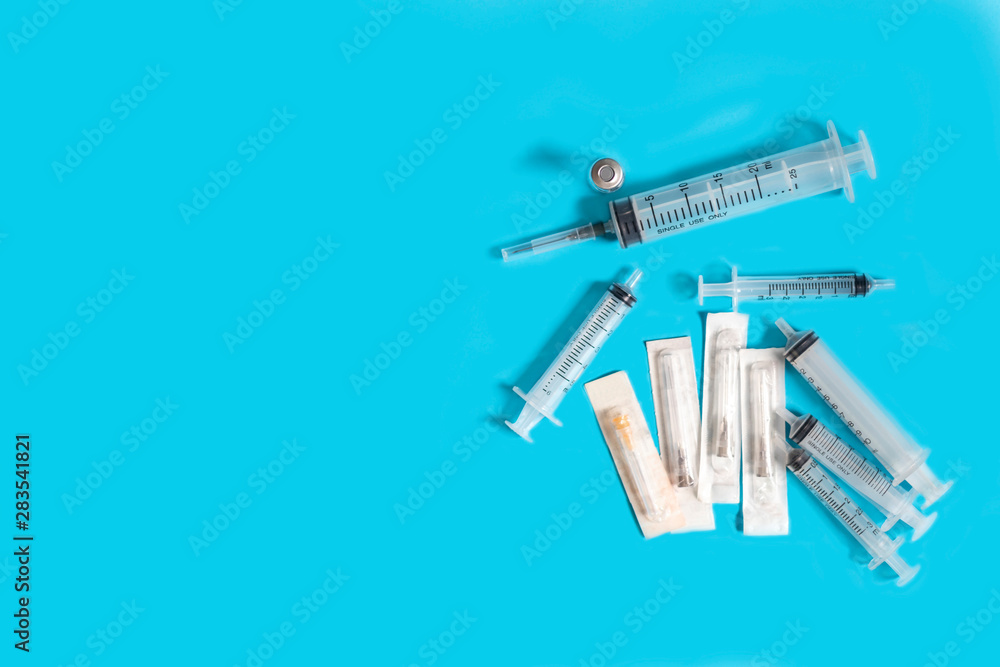 Vials with medication and injection needle on blue background. Top view Multiple syringes. Syringes that stack together. Copy space for text. Vials with medication and injection needle on blue background. Top view Multiple syringes. Syringes that stack together. Copy space for text.