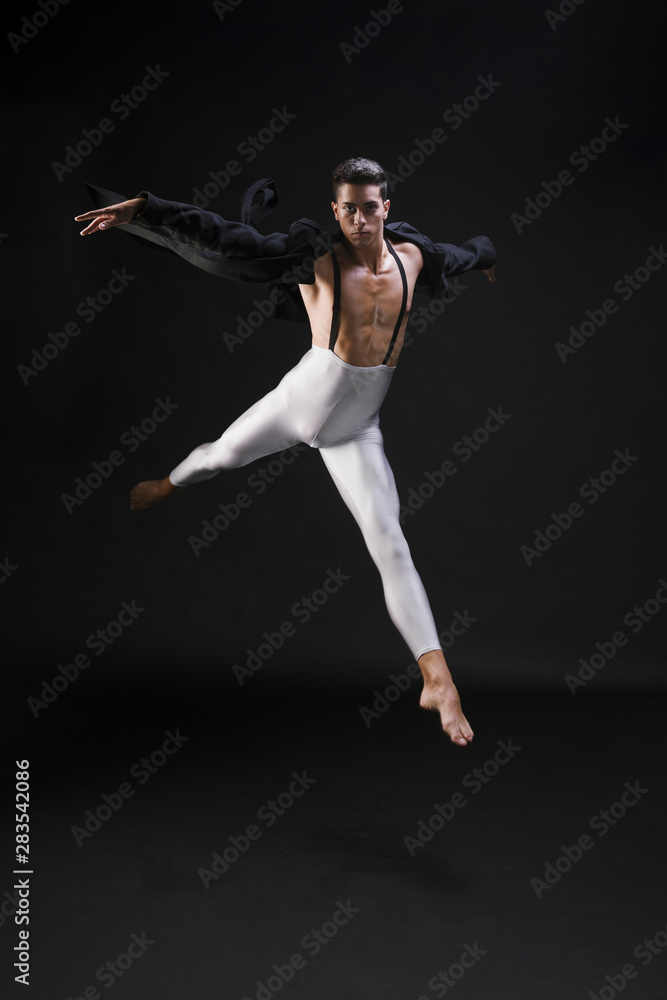 Young athletic male jumping and dancing on black background