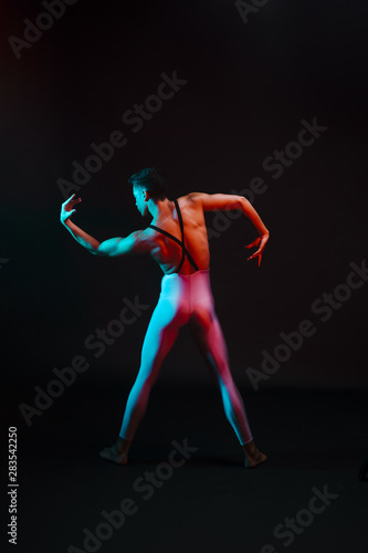 Unrecognizable ballet dancer in leotard with bent arms in spotlight