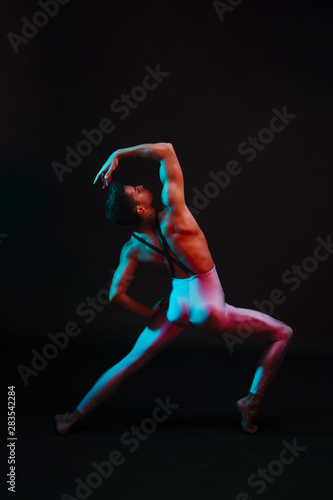 Unrecognizable ballet dancer arching back with legs apart in spotlight © Freepik